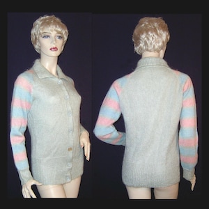 May include: A light gray cardigan with a collared neckline and button-up front. The sleeves feature horizontal stripes of pink and light blue. The cardigan is displayed on a mannequin, showcasing both the front and back views of the garment.