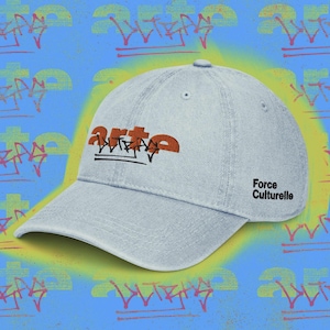 Peut inclure: Une casquette de baseball bleu clair avec un logo brodé orange et noir sur le panneau avant, affichant le texte "arte" et "ultras" dans un style graffiti. Le côté de la casquette présente le texte noir "Force Culturelle" en police sans-serif.