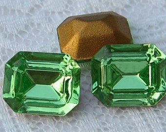 May include: Emerald-cut green gemstones and a gold-colored gemstone are displayed against a white lace background. The text "Quantity 4" is visible at the top of the image. The gemstones have a reflective surface.