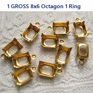 May include: A close-up of 10 gold-toned metal octagon-shaped settings with a single ring attached to each. The settings are designed to hold gemstones or other embellishments.
