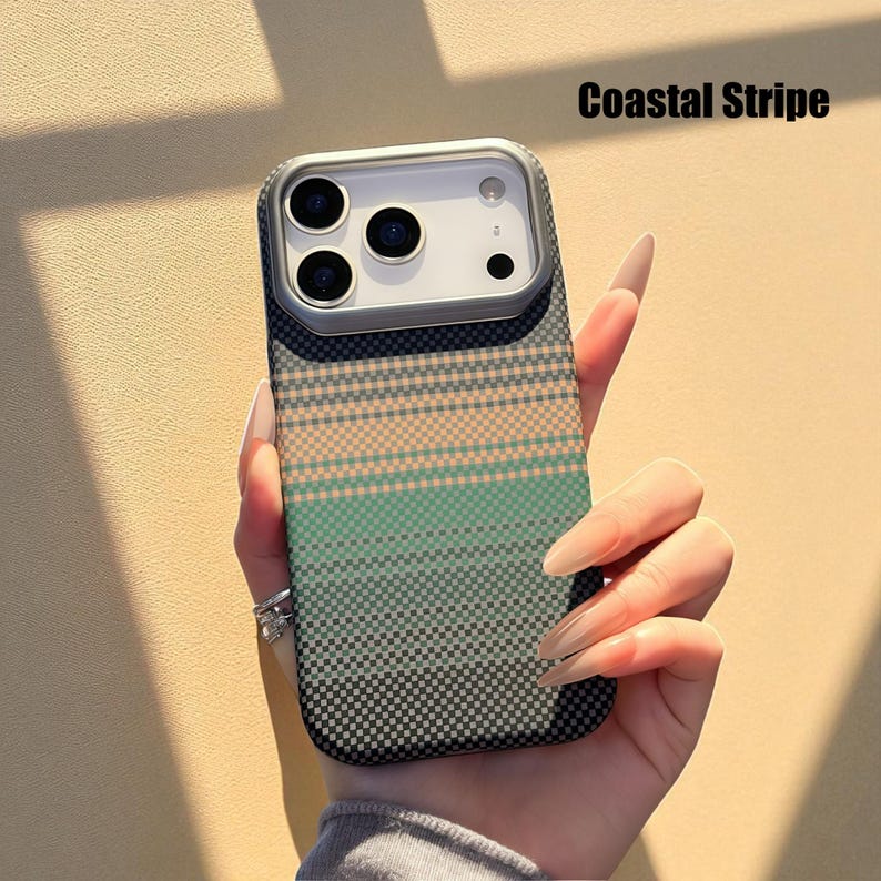 May include: A phone case with a Coastal Stripe design. The case features a pattern of horizontal stripes in shades of green, peach, and gray. The case has a camera cutout and is held by a person.