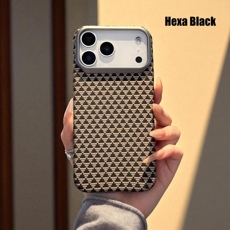 May include: A phone case with a geometric pattern of black triangles on a tan background. The case has a silver camera frame and the text "Hexa Black" in the upper right corner.
