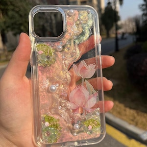 Pu&ograve; includere: Custodia per telefono trasparente con un design floreale rosa e verde e glitter. La custodia ha un bordo rialzato attorno all'obiettivo della fotocamera e un retro trasparente.