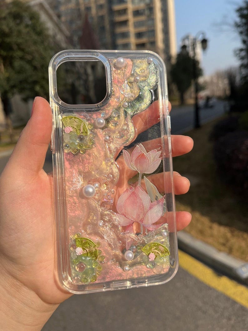 Pu&ograve; includere: Custodia per telefono trasparente con un design floreale rosa e verde e glitter. La custodia ha un bordo rialzato attorno all'obiettivo della fotocamera e un retro trasparente.