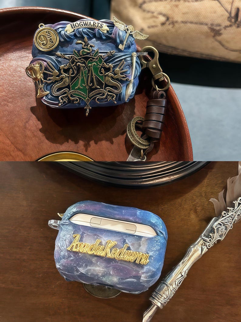 May include: A blue and gold Hogwarts themed phone case with a galaxy design and the name "Aurora Kedawra" written in gold lettering. The case is sitting on a wooden surface next to a silver pen.