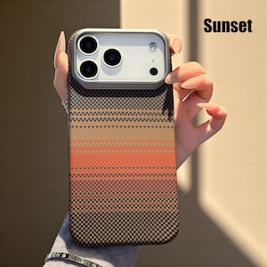 May include: A phone case with a sunset-themed design. The case features a gradient of colors, including brown, orange, and black, arranged in horizontal stripes. The word "Sunset" is printed in black on the top right corner.