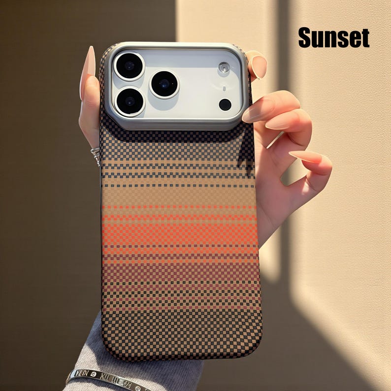 May include: A phone case with a sunset-themed design. The case features a gradient of colors, including brown, orange, and black, arranged in horizontal stripes. The word "Sunset" is printed in black on the top right corner.