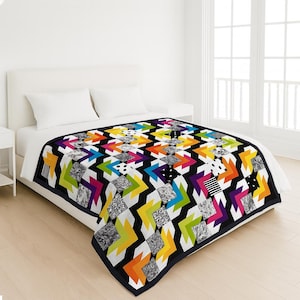 May include: A vibrant quilt featuring a geometric design of zigzags and diamond shapes in black, white, and a spectrum of colours. The quilt, with a black border, is displayed on a white bed. The quilt measures approximately 203 cm by 152 cm.