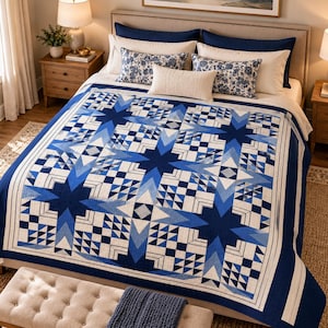 Könnte beinhalten: Ein Steppdecke mit einem geometrischen Muster aus großen blauen Sternen und kleineren karierten Quadraten in Marineblau, Königsblau und Weiß. Das Design umfasst einen breiten weißen Rand und komplexe, zusammengesetzte Blöcke mit Sternmotiven.