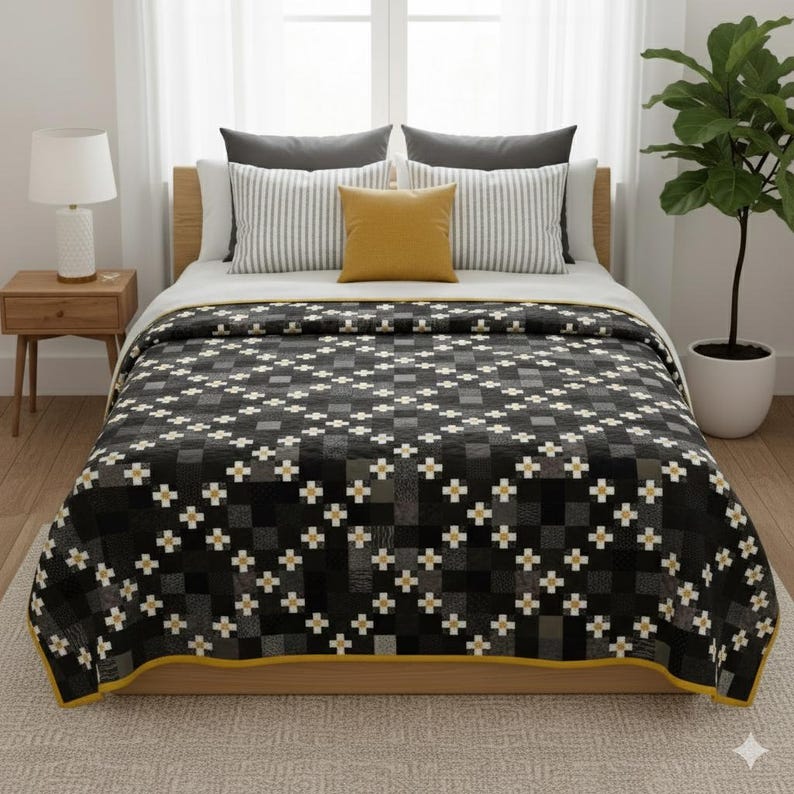May include: A bed with a black, gray, and white patterned quilt. The quilt has a yellow border and is decorated with a cross-like design. The bed also has gray and white striped pillows, a yellow pillow, and a wooden bed frame.