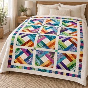 Könnte beinhalten: Eine Tagesdecke mit einem sich wiederholenden quadratischen Blockmuster mit diagonalen Streifen in einem Regenbogen aus Farben wie Blau, Grün, Violett, Orange und Gelb, getrennt durch einfarbige weiße Zwischenstreifen und einen weißen Rand auf einem Bett.