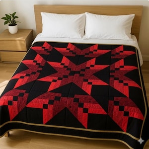 以下が含まれることがあります： 白い枕と木のヘッドボードが付いたベッドに飾られた、星柄の赤と黒のキルト。キルトは、黒い縁と金色のトリムを備えた幾何学模様が特徴です。キルトは居心地の良い寝具アイテムです。