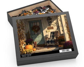 May include: A 500-piece jigsaw puzzle in a black box featuring a 16x20 inch image of a porch with a teal door, a wreath, a wooden chair with a plaid blanket, pumpkins, and autumn flowers. The box lid displays the text 16x20 Puzzle 500 pcs Ages 9+.