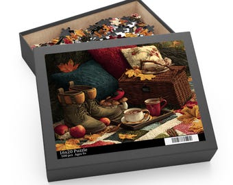 May include: A 500-piece jigsaw puzzle in a black box featuring an autumn scene with brown boots, a wicker basket, red mugs, apples, and fallen leaves. The box lid displays the text 16x20 Puzzle 500 pcs Ages 9+ and a barcode, with puzzle pieces visible inside.