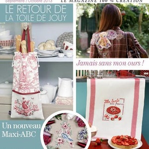 May include: A magazine cover featuring a cross-stitch design of a red and white toile pattern with the text "Le Retour de la Toile de Jouy" and "Un nouveau Maxi-ABC". The cover also features a cross-stitch design of a red and white striped kitchen towel with the text "Ma tarte aux fraises" and "La cuisine au point de croix en 5 styles".
