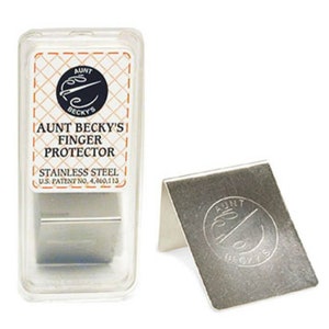 May include: A stainless steel finger protector for sewing, with the words "Aunt Becky's Finger Protector" and "Stainless Steel" printed on the packaging. The protector is in a clear plastic case.