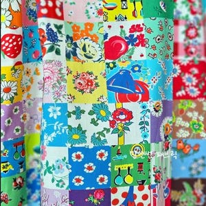 May include: A patchwork textile featuring a vibrant array of floral and patterned squares. The design incorporates various colors, including red, blue, yellow, and green, with images of flowers, fruits, and other decorative elements. The fabric is likely used for quilting or crafting.