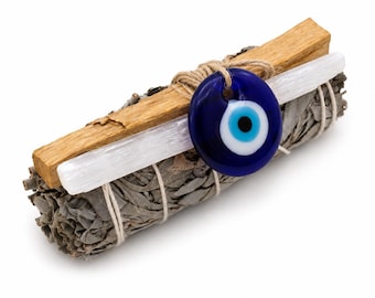 May include: A bundle of dried sage leaves tied with twine, topped with a rectangular piece of light brown wood and a white selenite crystal wand. A circular blue, white, and black glass evil eye charm is attached to the center of the bundle.