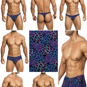 Op de afbeelding: Collectie heren zwemkleding, waaronder slips, strings en zwemshorts. De zwemkleding heeft een levendig, herhalend patroon van gestileerde bladeren in tinten blauw, paars en groen op een zwarte achtergrond.