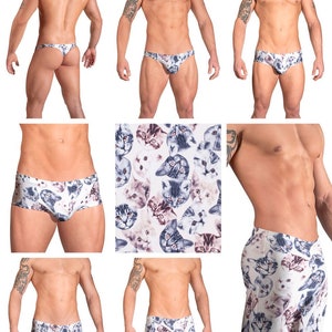 May include: A set of underwear with a cat print. The underwear comes in three styles: a thong, a brief, and a boxer short. The print features a white background with a variety of cats in different colors and poses.