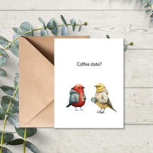 May include: A greeting card with a brown envelope. The card features two cartoon birds, one red and one yellow, wearing hoodies and holding coffee cups. The text "Coffee date?" is above the birds.