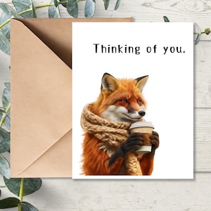 May include: A greeting card with a fox wearing a scarf and holding a cup of coffee. The card says "Thinking of you."