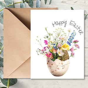 May include: A white card with the text "Happy Easter" in black script. A watercolor illustration of a cracked eggshell filled with a bouquet of colorful wildflowers.