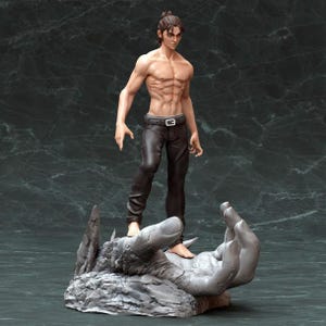 K&ouml;nnte beinhalten: Eine Skulptur eines Mannes mit muskul&ouml;sem K&ouml;rperbau, der auf einem gro&szlig;en, grauen, handf&ouml;rmigen Sockel steht. Der Mann tr&auml;gt eine schwarze Hose und hat einen kurzen, dunklen Pferdeschwanz.