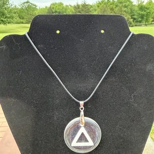 Colgante de resina con signo de recuperación de triángulo en un círculo en cadena de 18”.