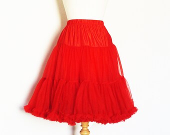 May include: A red tulle petticoat with multiple layers and a ruffled hem. The petticoat is displayed on a wooden mannequin.