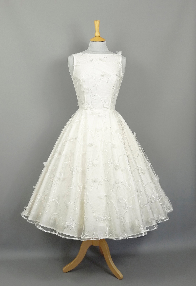 May include: A white sleeveless wedding dress with a full skirt and delicate floral embroidery.
