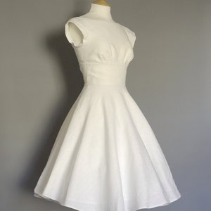 Puede incluir: Un vestido blanco sin mangas con un corpi&ntilde;o ajustado y una falda completa. El vestido est&aacute; en un maniqu&iacute; de madera.