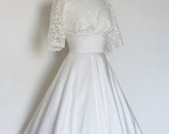 May include: A white vintage wedding dress with a lace bodice and a full skirt.