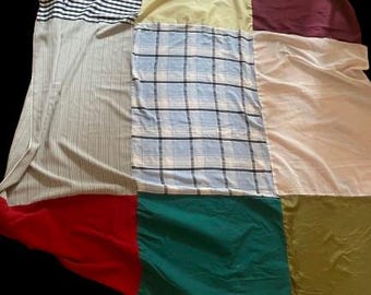 May include: A patchwork quilt made from different fabrics in various colors and patterns, including stripes, plaid, and solid colors. The quilt is made up of nine squares, each with a different fabric.