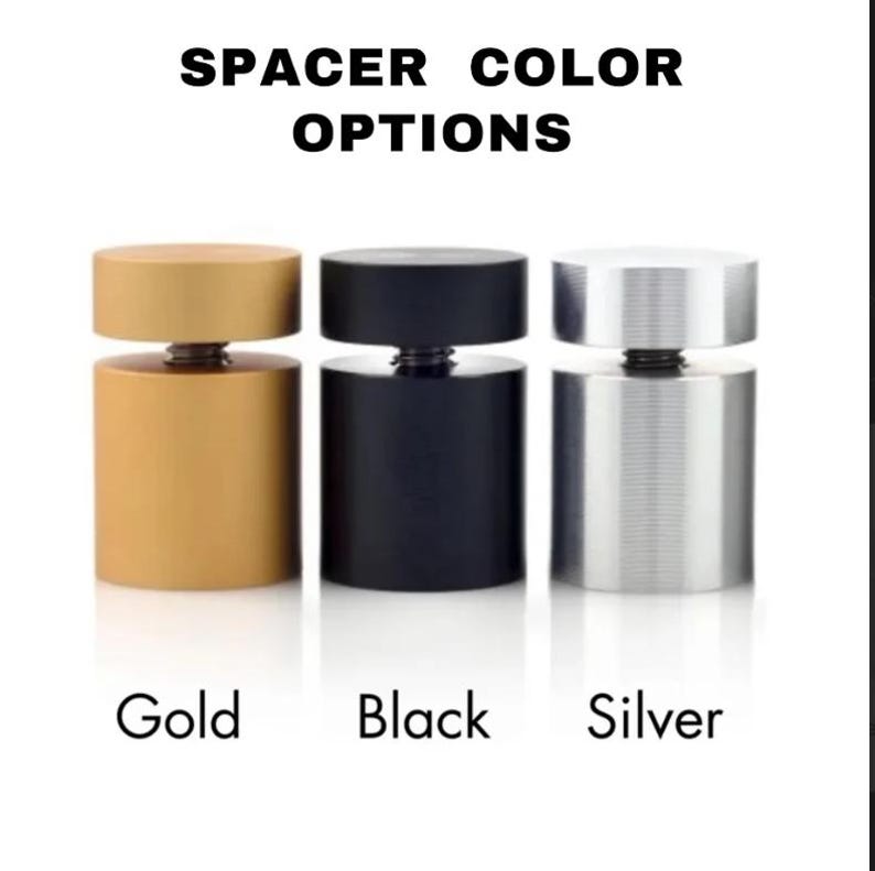 May include: Image shows three cylindrical spacers in gold, black, and silver. Each spacer has a round top and bottom, connected by a threaded screw. The text "SPACER COLOR OPTIONS" is at the top, with the colors labeled below each spacer.