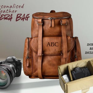 Könnte beinhalten: Braune Leder-Kameratasche mit personalisiertem Monogramm. Der Rucksack hat mehrere Fächer und Riemen. Eine Kamera und eine Innentasche sind ebenfalls im Bild enthalten.