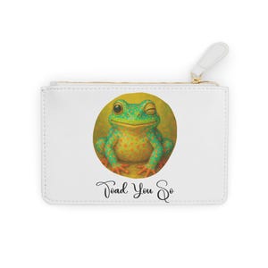 May include: White zippered pouch with a winking frog illustration. The frog is green with orange spots, set against a yellow circle. The text "Toad You So" is written below. The pouch has a white pull tab and a gold-colored zipper.