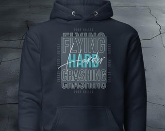 May include: A dark blue hoodie with a white graphic print that says "Prop Killer Flying Harder Crashing Crashing Prop Killer" with the words "Flying" and "Harder" in a teal blue color.