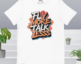 Puede incluir: Camiseta blanca con un estampado gráfico colorido que dice "FLY MORE TALK LESS" en estilo graffiti.