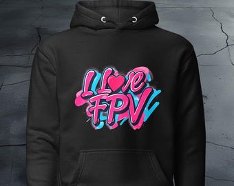 May include: Black hoodie with a graphic print of the words "I Love FPV" in pink, blue, and white graffiti style. The heart in the graphic is pink.