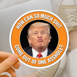 May include: A circular sticker with an orange border. The text "HOW CAN SO MUCH SHIT COME OUT OF ONE ASSHOLE?" encircles a photo of a man with blonde hair and a red tie making a kissing face.