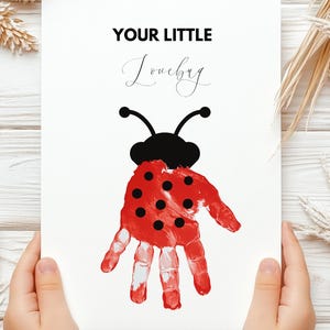 Op de afbeelding: Een witte kaart met de tekst "YOUR LITTLE Lovebug" bovenaan. Een rode lieveheersbeestje met zwarte stippen is op de kaart gedrukt, gemaakt met een handafdruk.