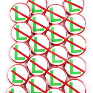 May include: A collection of round white buttons with a red border. Each button features a green letter "L" with a red diagonal line through it. The buttons are arranged closely together against a white background.