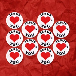 Könnte beinhalten: Zehn weiße runde Knöpfe mit roten Herzen und dem Text "Jesus Loves You" in Schwarz.