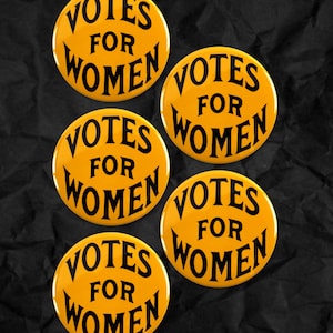 Könnte beinhalten: Fünf gelbe runde Buttons mit dem Text "VOTES FOR WOMEN" in Schwarz. Die Buttons sind auf einem strukturierten schwarzen Hintergrund angeordnet. Die Buttons sind im Vintage-Stil.