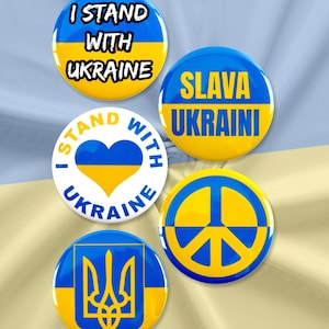 May include: Five round buttons with blue and yellow colors and various messages in support of Ukraine. The buttons say "I Stand With Ukraine", "I Stand With Ukraine" with a heart, "Slava Ukraini", a peace sign, and the Ukrainian coat of arms.
