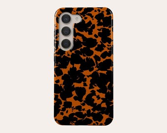 May include: A phone case with a tortoiseshell pattern. The case features a repeating design of black, irregular shapes against a warm, orange-brown background. The case has a camera module with three lenses.