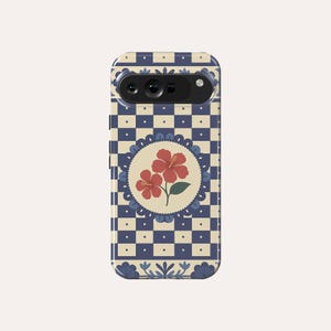 May include: A phone case with a blue and cream checkerboard design. The case features a circular design with two red hibiscus flowers and green leaves. The case has a camera cutout and floral accents.
