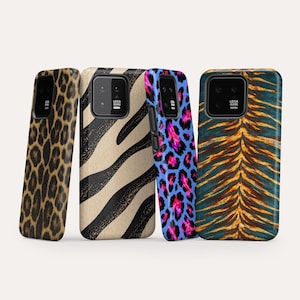 May include: Four smartphone cases featuring distinct animal-inspired patterns. From left to right: a brown and black leopard print, a beige and black zebra stripe, a blue and pink leopard print, and a dark teal and orange tiger stripe pattern.