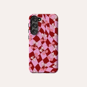 May include: A pink and red phone case with a checkered pattern and cherries with bows.